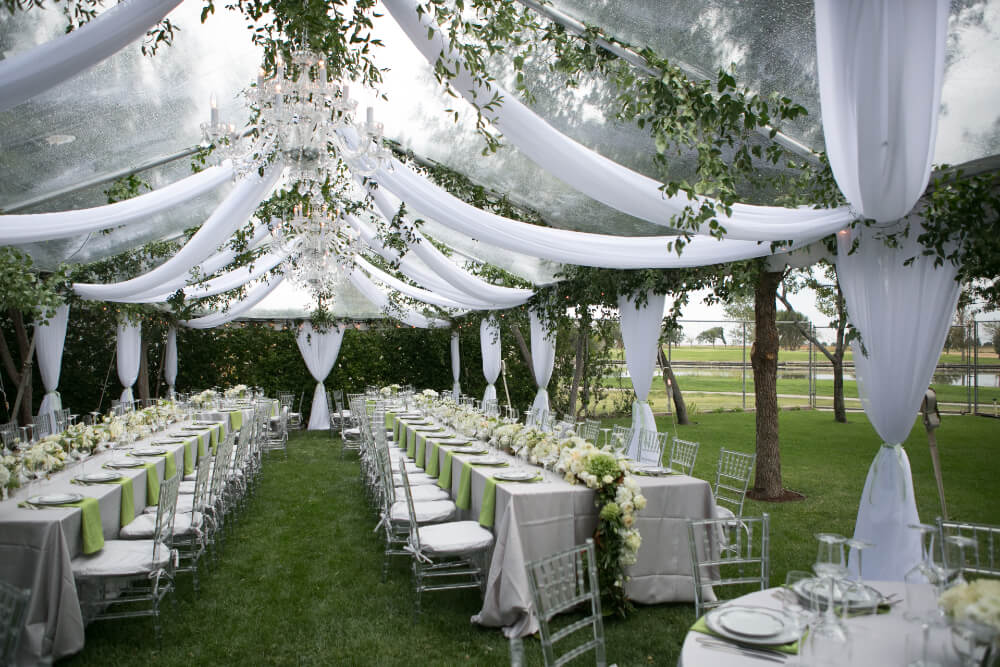Outdoor Summer Wedding Tent Decorated With Hanging Fabric Greenery And Crystal Chandeliers 